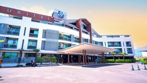 A modern hotel with a prominent 'URITEL' sign, multiple balconies, and a covered entrance area.