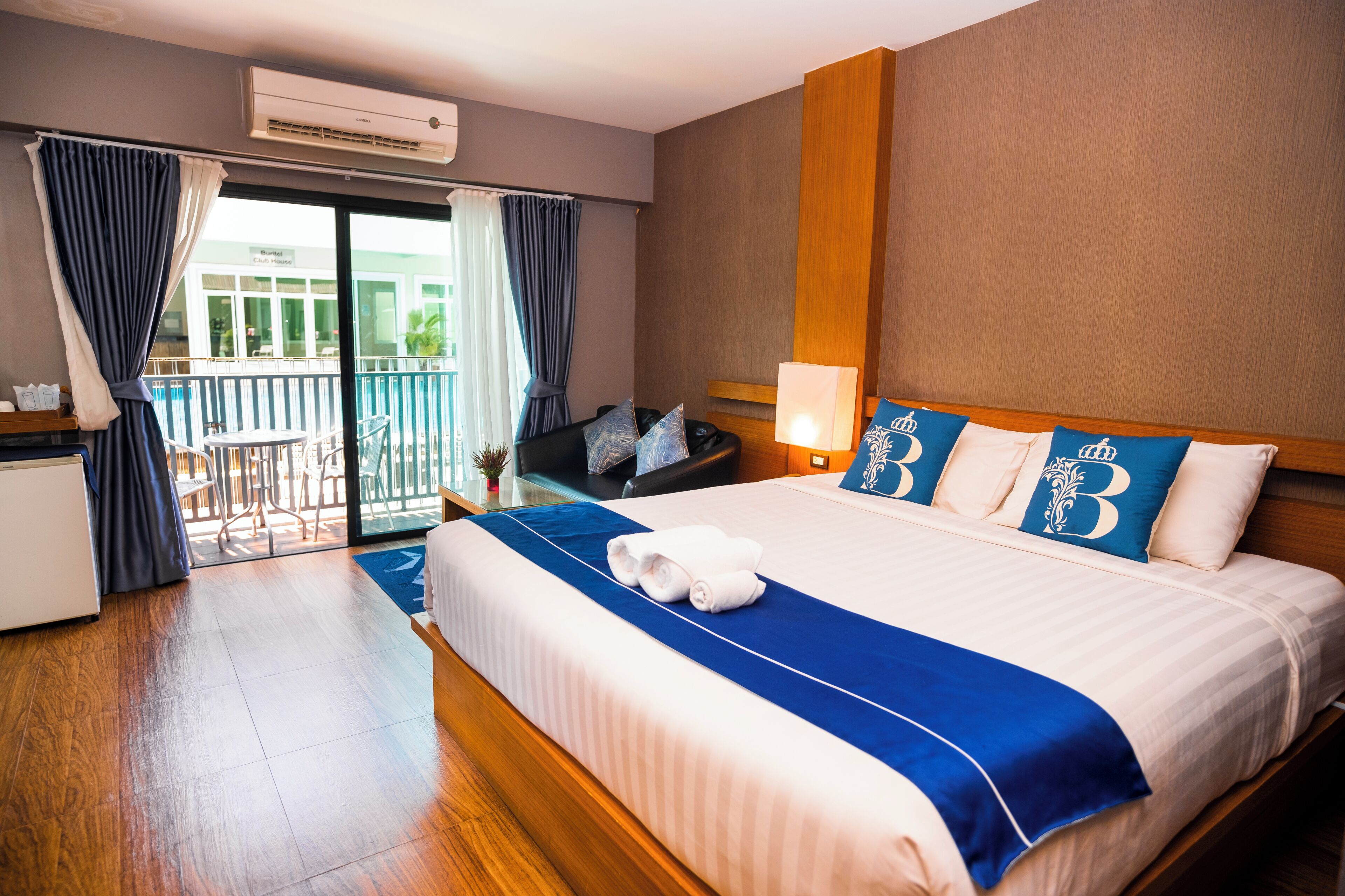 A hotel room with a large bed, a desk, a chair, and a balcony with a view.