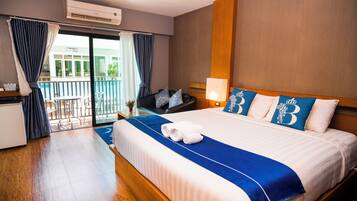 A hotel room with a large bed, a desk, a chair, and a balcony with a view.