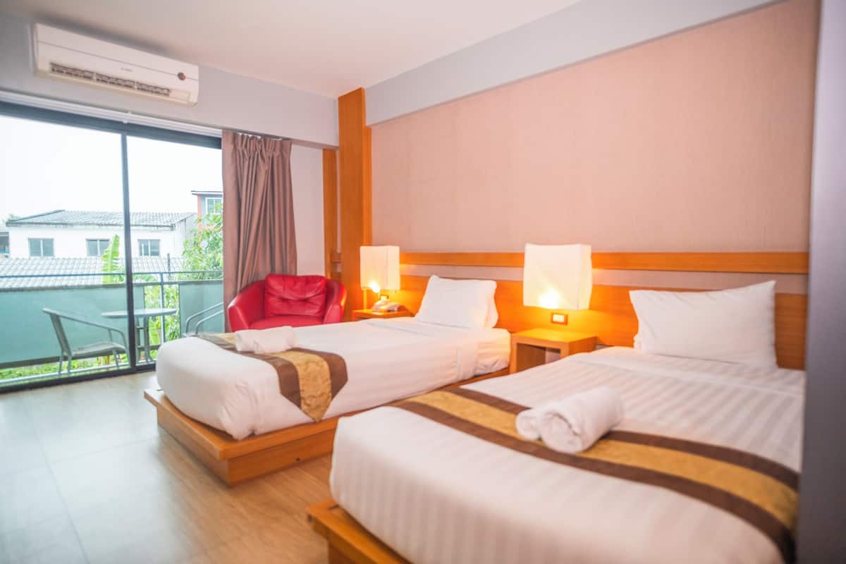 A hotel room with two beds, a red chair, a balcony with a view, and an air conditioning unit.