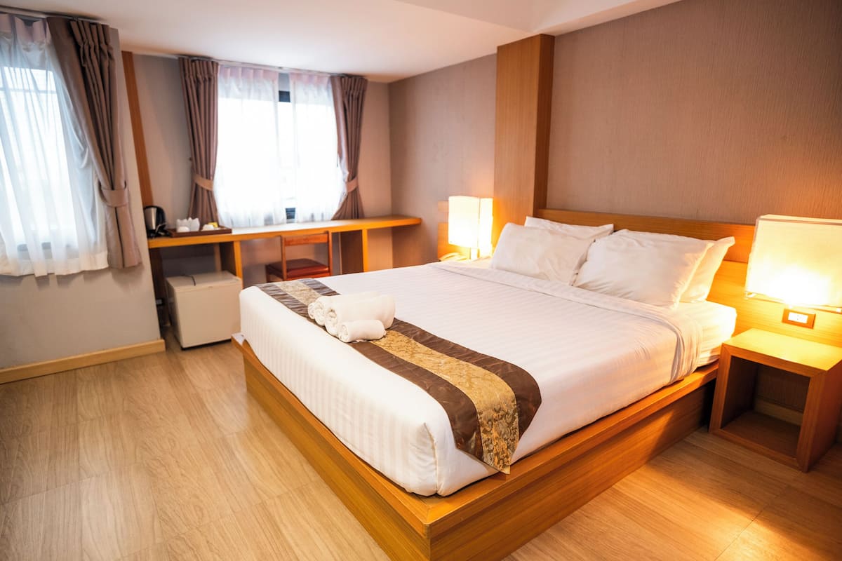 A hotel room with a large bed, bedside tables, a desk, and a chair.