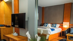 A hotel room with a bed, bedside table, TV, and a mirror.