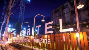 A hotel entrance with a large illuminated sign spelling 'GURITEL' and 'WUSINA' in both English and another language.