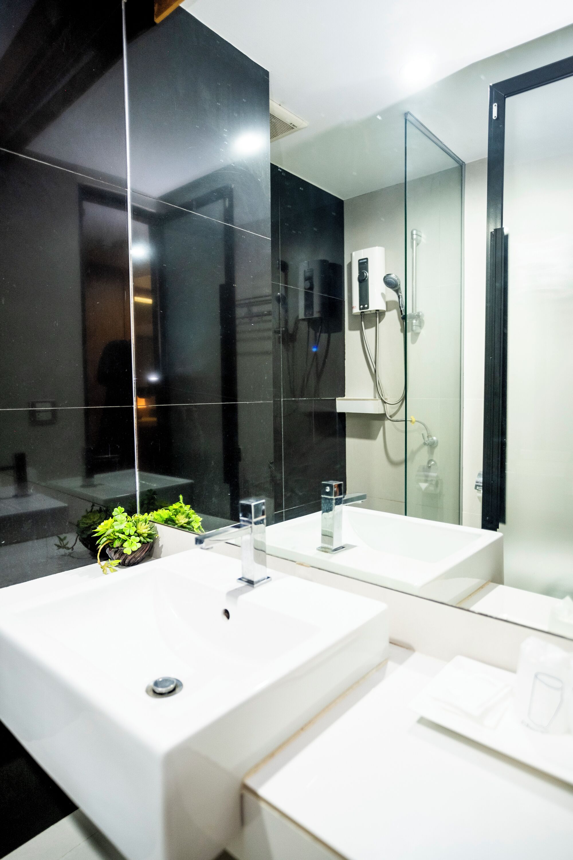 Ein modernes Badezimmer mit zwei Waschbecken, einer Glasdusche und einem großen Spiegel.
