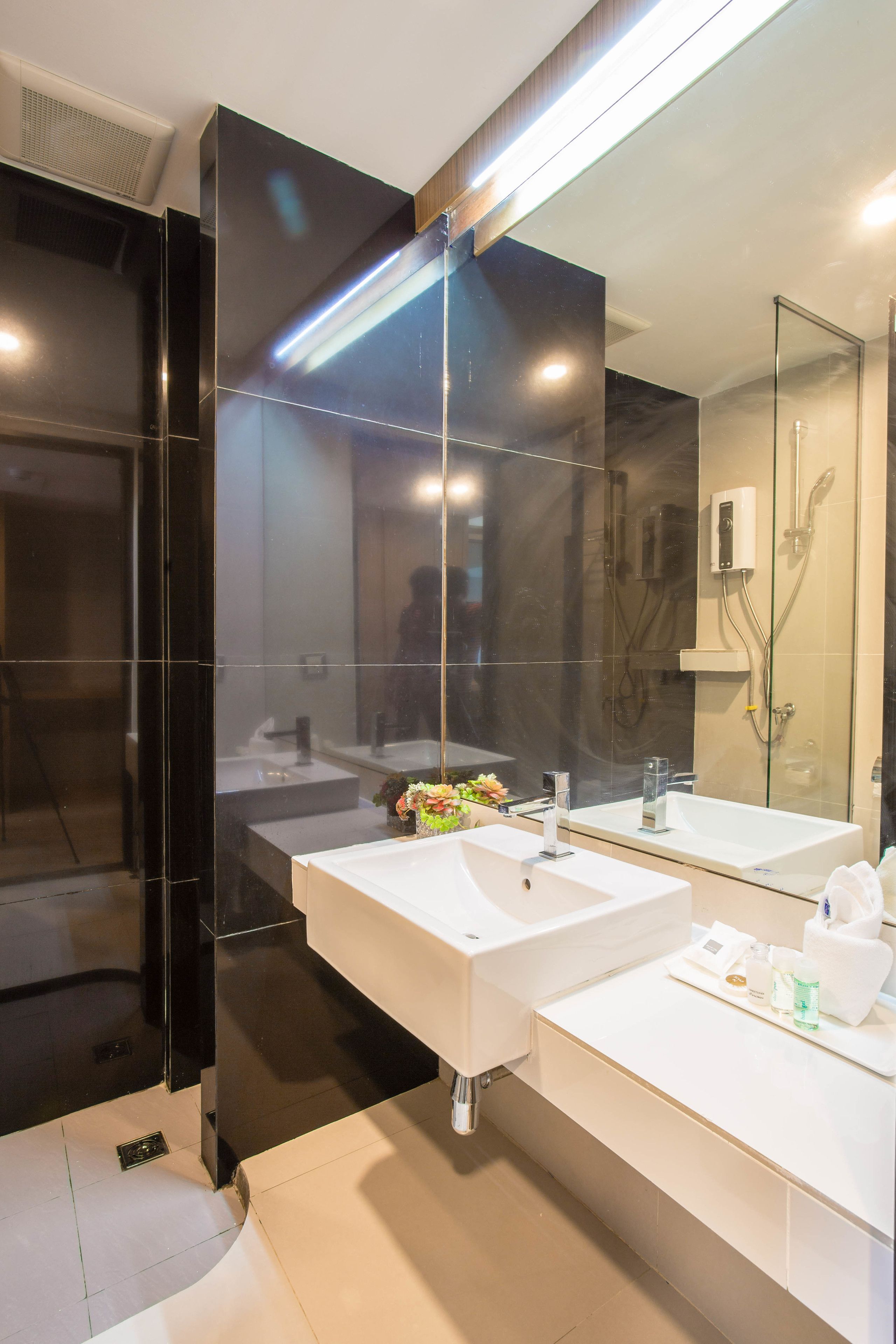 A modern bathroom with two sinks, a large mirror, and a glass shower enclosure.