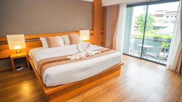 Ein Hotelzimmer mit einem großen Bett, einem hölzernen Kopfteil, Nachttischlampen und Blick ins Freie durch eine Glastür.