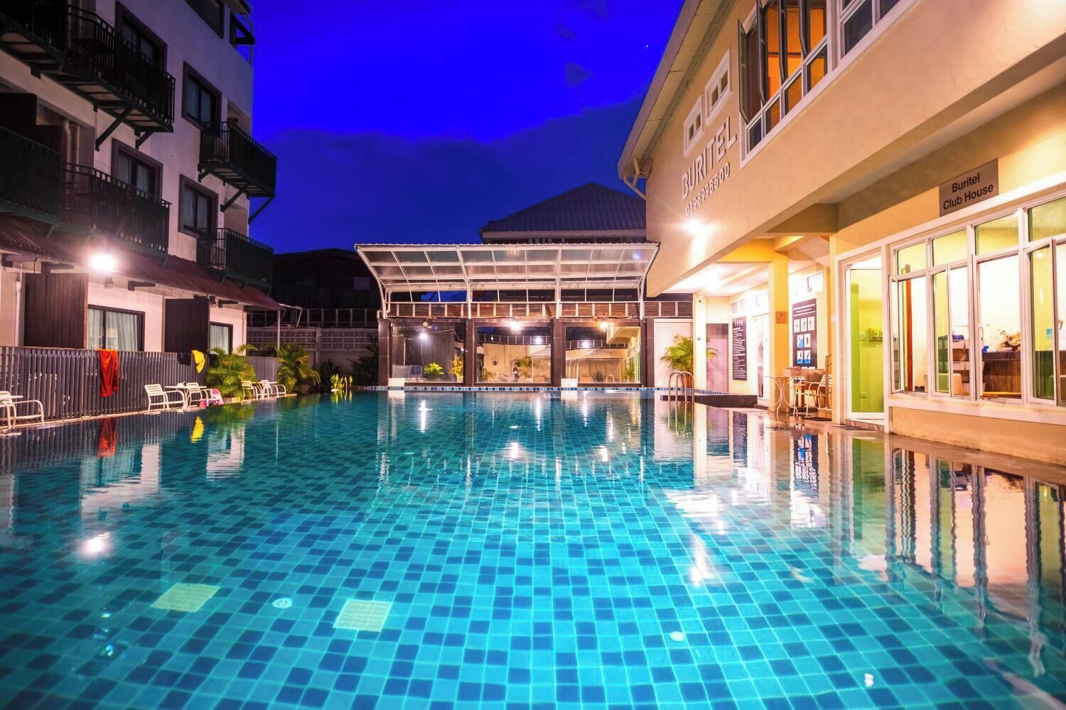 Una piscina interior con baldosas azules brillantes, rodeada de edificios con balcones y ventanas.