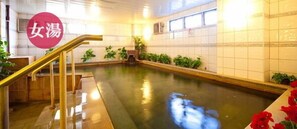 Ein Schwimmbecken mit einer Holzterrasse und einer Metalltreppe zum Wasser.