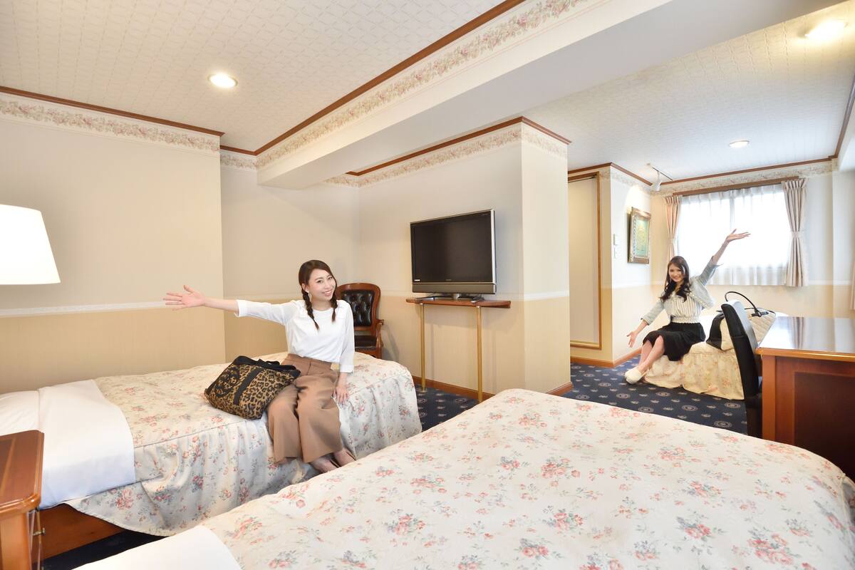 Una habitación de hotel con dos camas, televisión y escritorio.