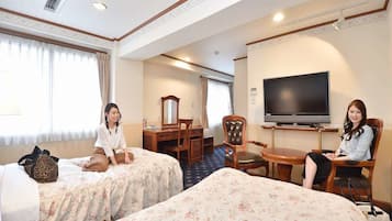 A hotel room with two beds, a desk, a chair, a TV, and a window with curtains.