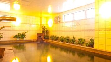 A swimming pool with tiled walls and a tiled floor, surrounded by potted plants.