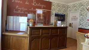 A reception desk with a wooden finish, a large sign with text, a computer monitor, and a door labeled "BLOIS CHAMBORD CHEVERNY".