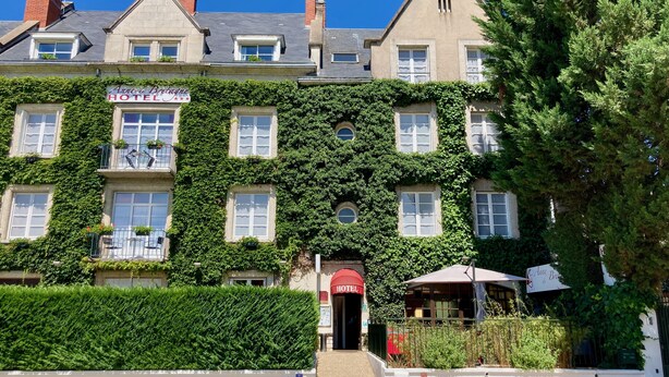 A hotel with a classic European architectural style, featuring a symmetrical facade, multiple windows, and a prominent entrance with a red door.