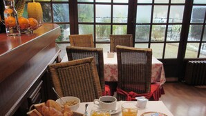 A breakfast table with bread, pastries, fruit, and beverages.