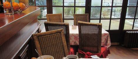 A breakfast table with bread, pastries, fruit, and beverages.