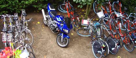 Een parkeerplaats met meerdere fietsen en een scooter.