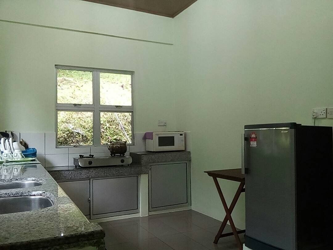 Une cuisine de taille réduite, dotée d’une fenêtre, d’un four à micro-ondes, d’une cuisinière et d’un réfrigérateur.