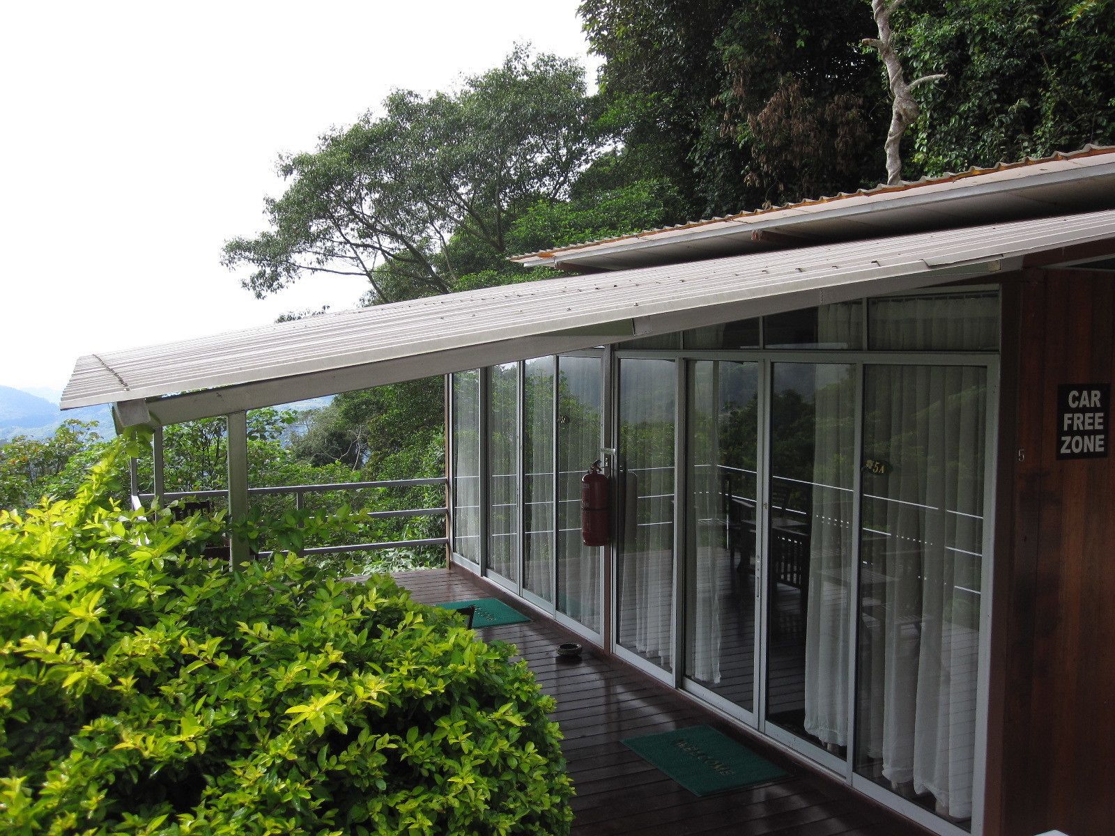 A modern building with a covered outdoor area, large glass windows, and a sign indicating a car-free zone.