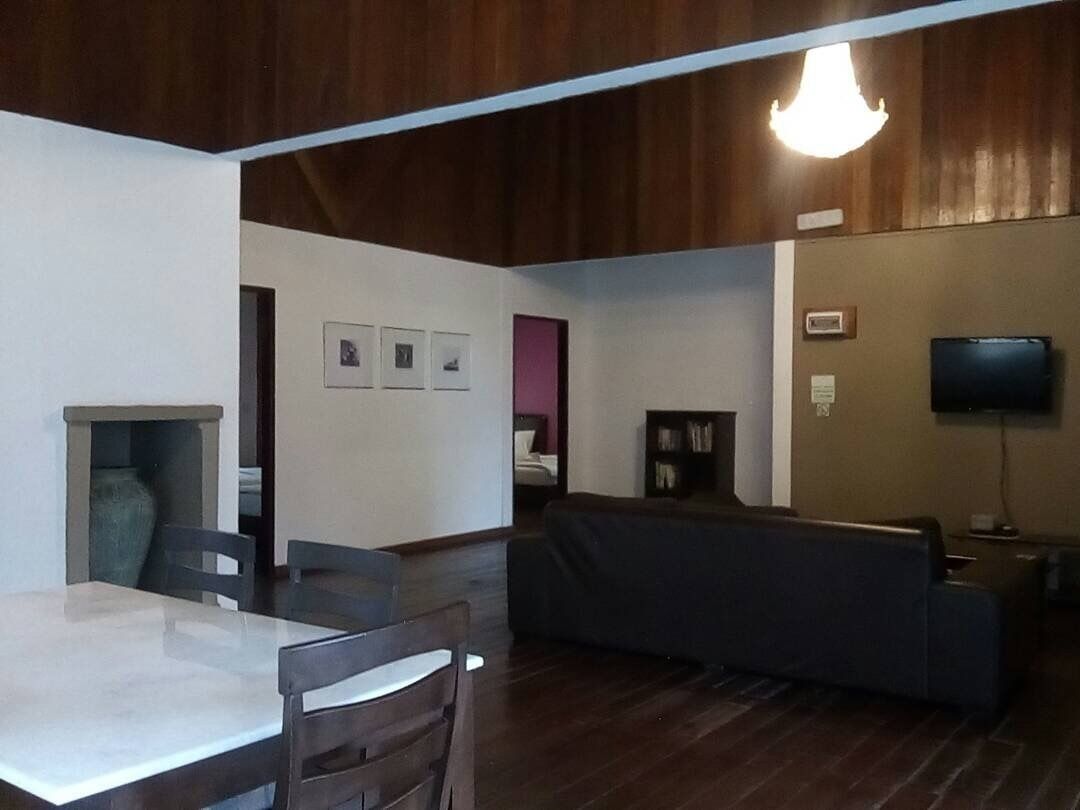 Una habitación con una mesa de comedor, sillas, un sofá, un televisor y una estantería.