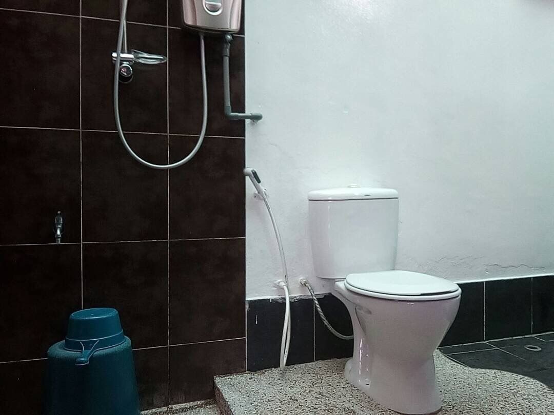 Kylpyhuoneessa on wc, suihku ja sininen vesipullo lattialla.