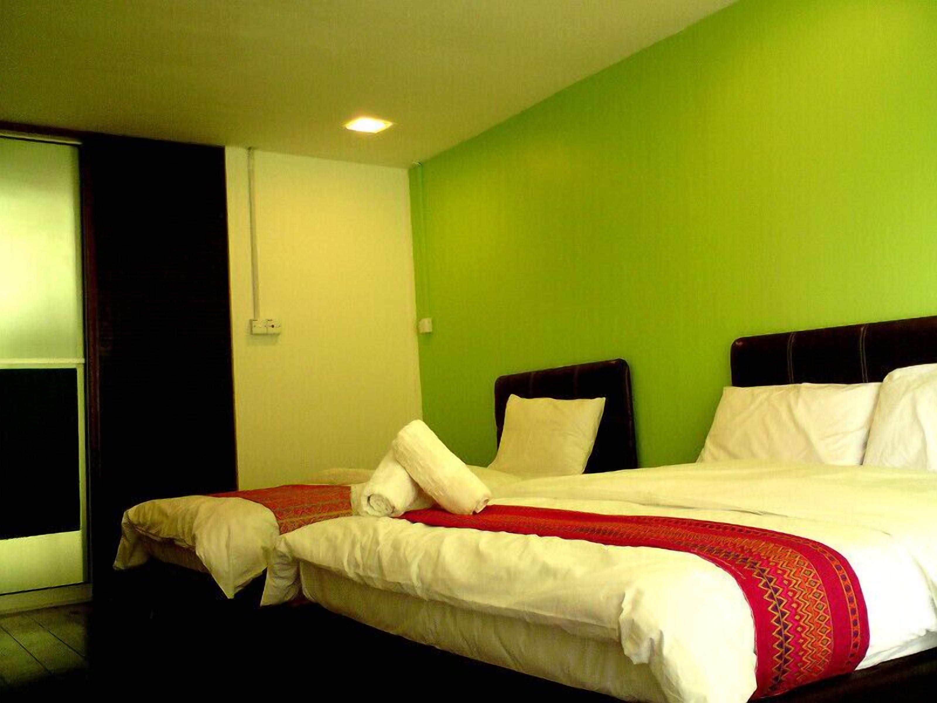 Habitación de hotel con una cama, una ventana y una pared verde.