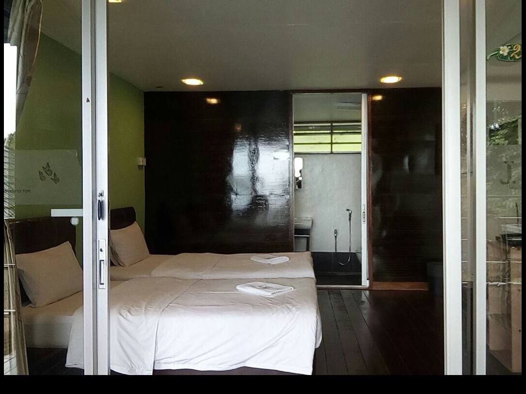 A hotel room with a large bed, a shower area, and a glass door leading to the outside.