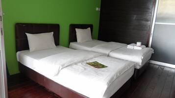 Een tweepersoonsbed met witte lakens, een groene wand en een donker houten hoofdeinde.