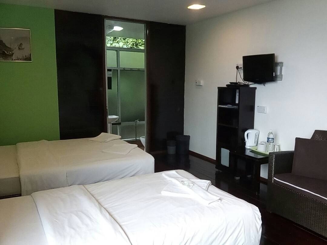 Ein Hotelzimmer mit zwei Betten, einem Fernseher, einem kleinen Tisch und einem Sofa.