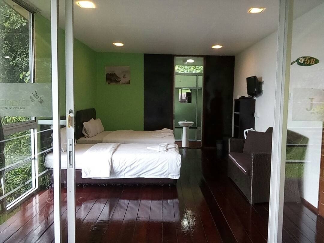 Quarto de hotel com cama, escrivaninha, cadeira, pia e espelho.