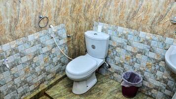 A bathroom with a toilet, a trash bin, and a sink.