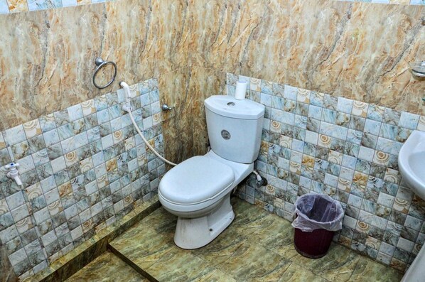 A bathroom with a toilet, a trash bin, and a sink.