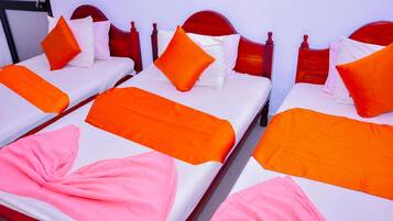 Three single beds with wooden headboards, white bedding, and orange and pink accents.