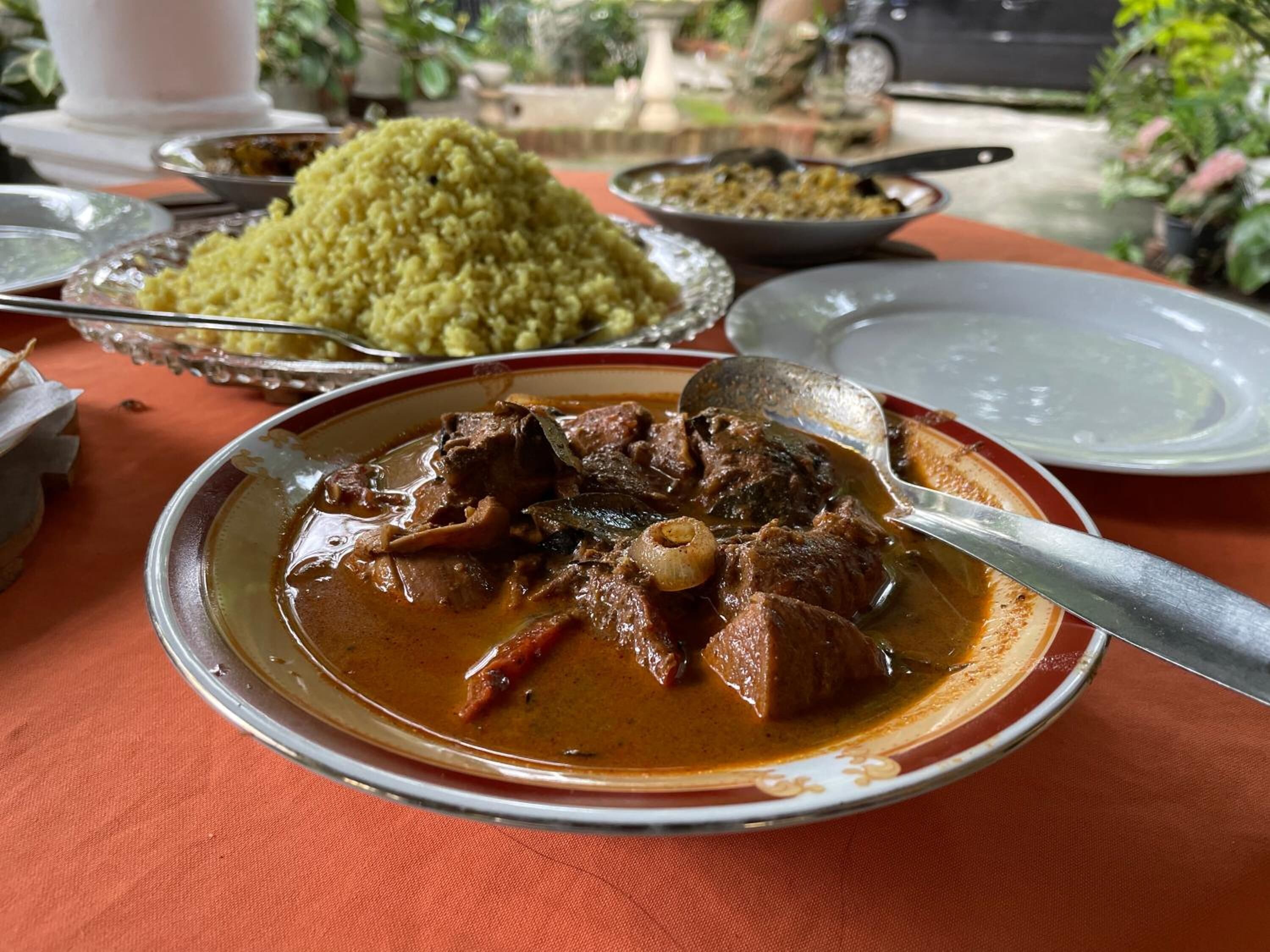 A meal with a stew and rice, served on a table with a red tablecloth.