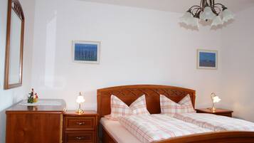 A bedroom with a wooden bed, bedside tables, a nightstand, and a chandelier.