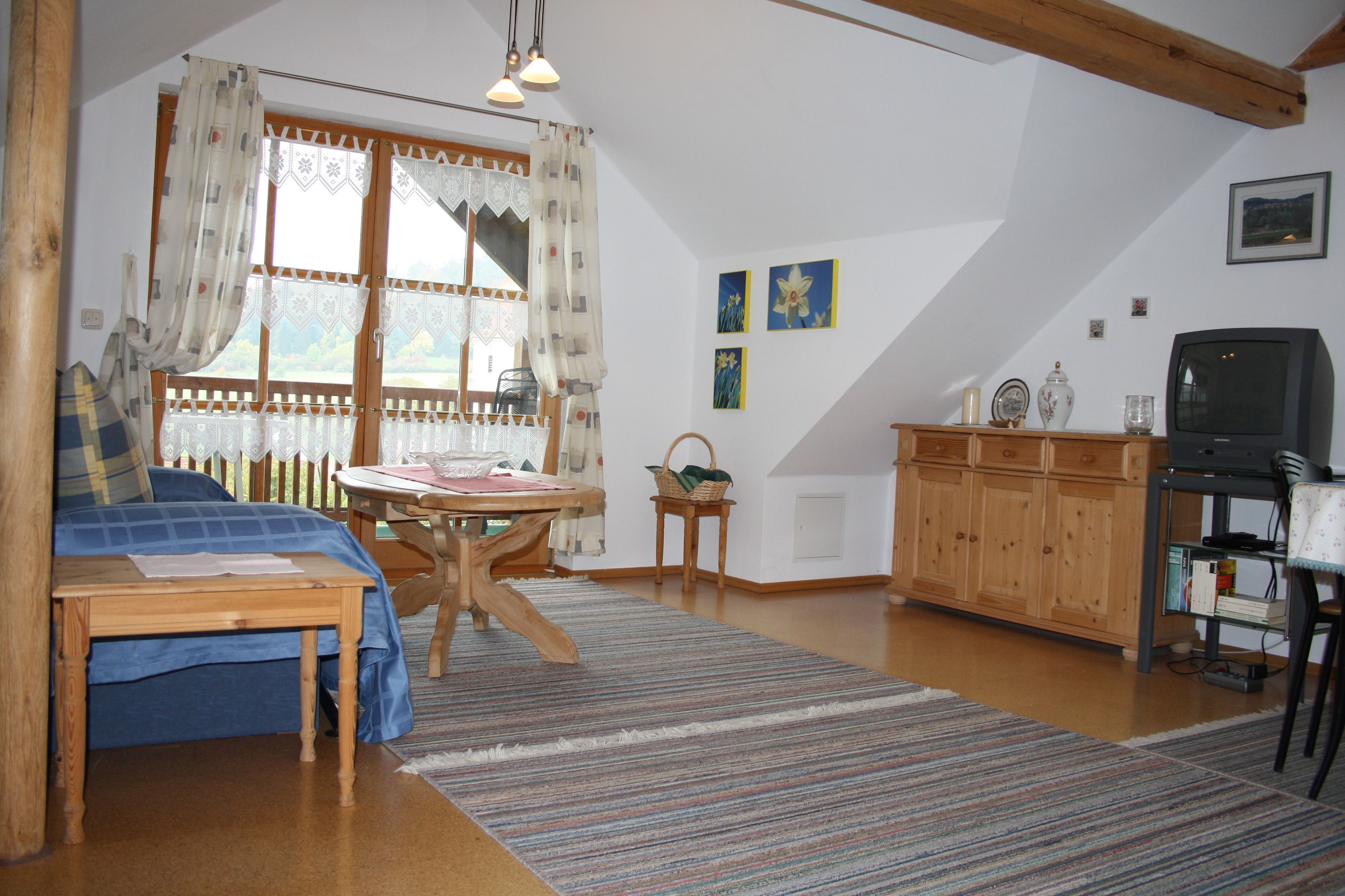 A cozy room with a bed, a wooden table, a television, and a cabinet.