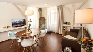 A modern living room with a dining table, white chairs, a sofa, a TV, and a lamp. - Boardinghouse Luise 5 (Heidelberg)