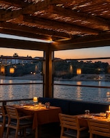 Un restaurante con vistas a un río y edificios al otro lado del agua.