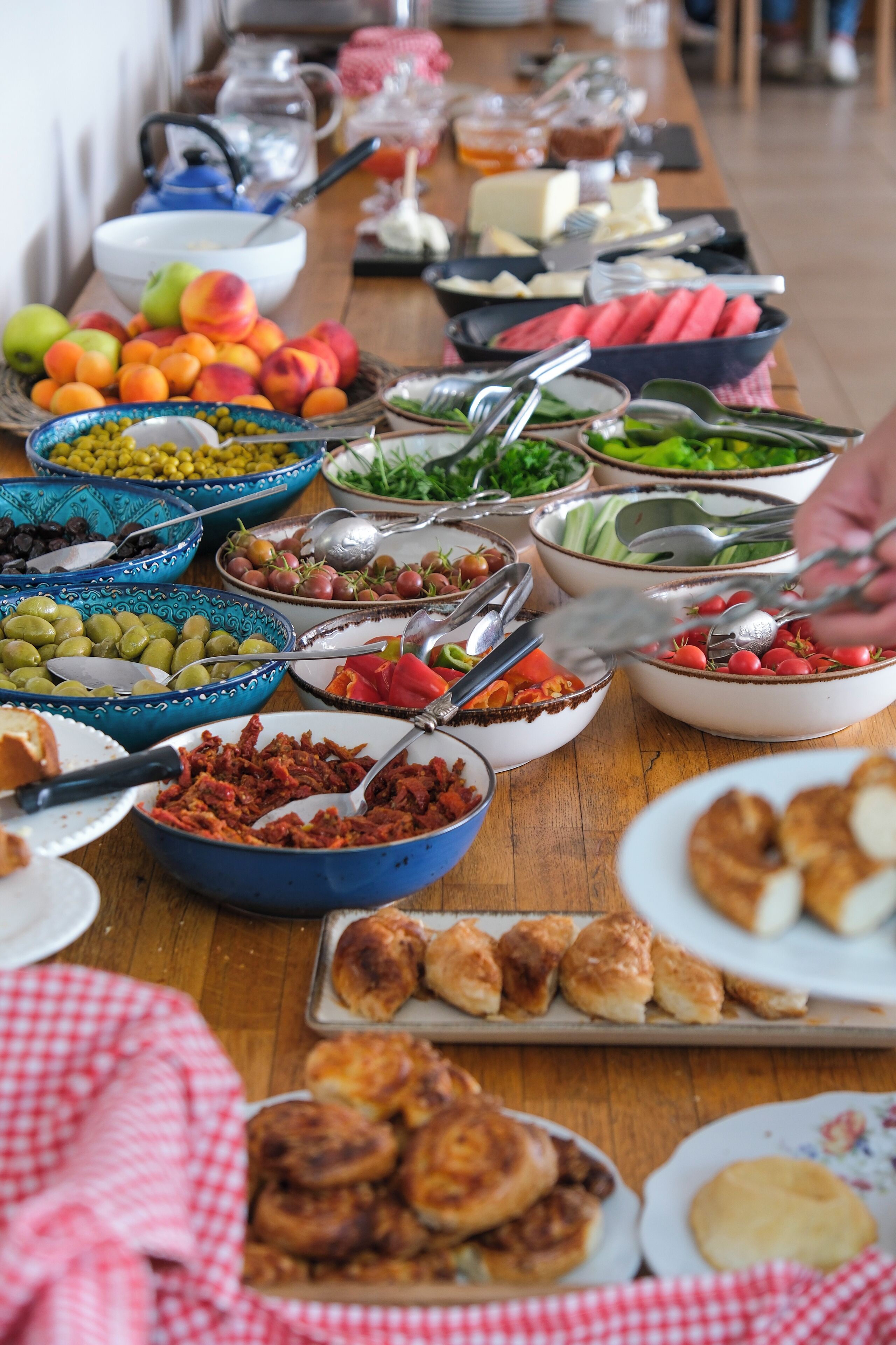 A buffet table with various food items and utensils.