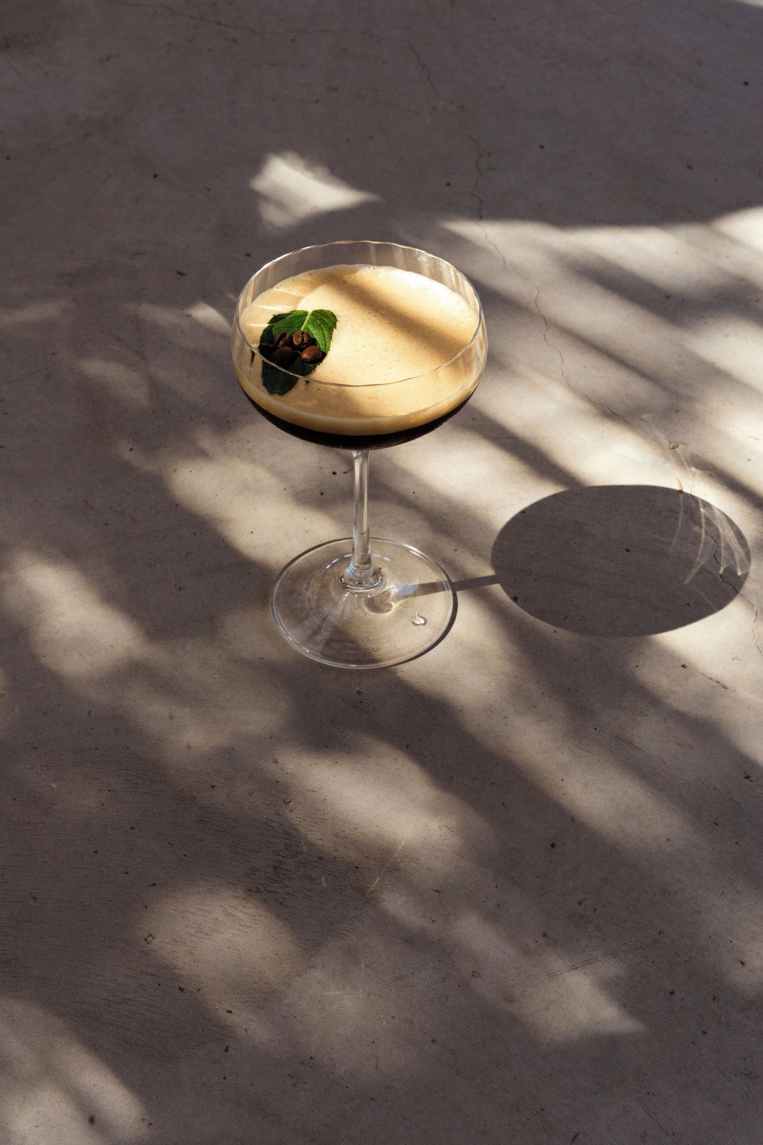 Een martini glas met een schuimend drankje op een marmeren oppervlak.