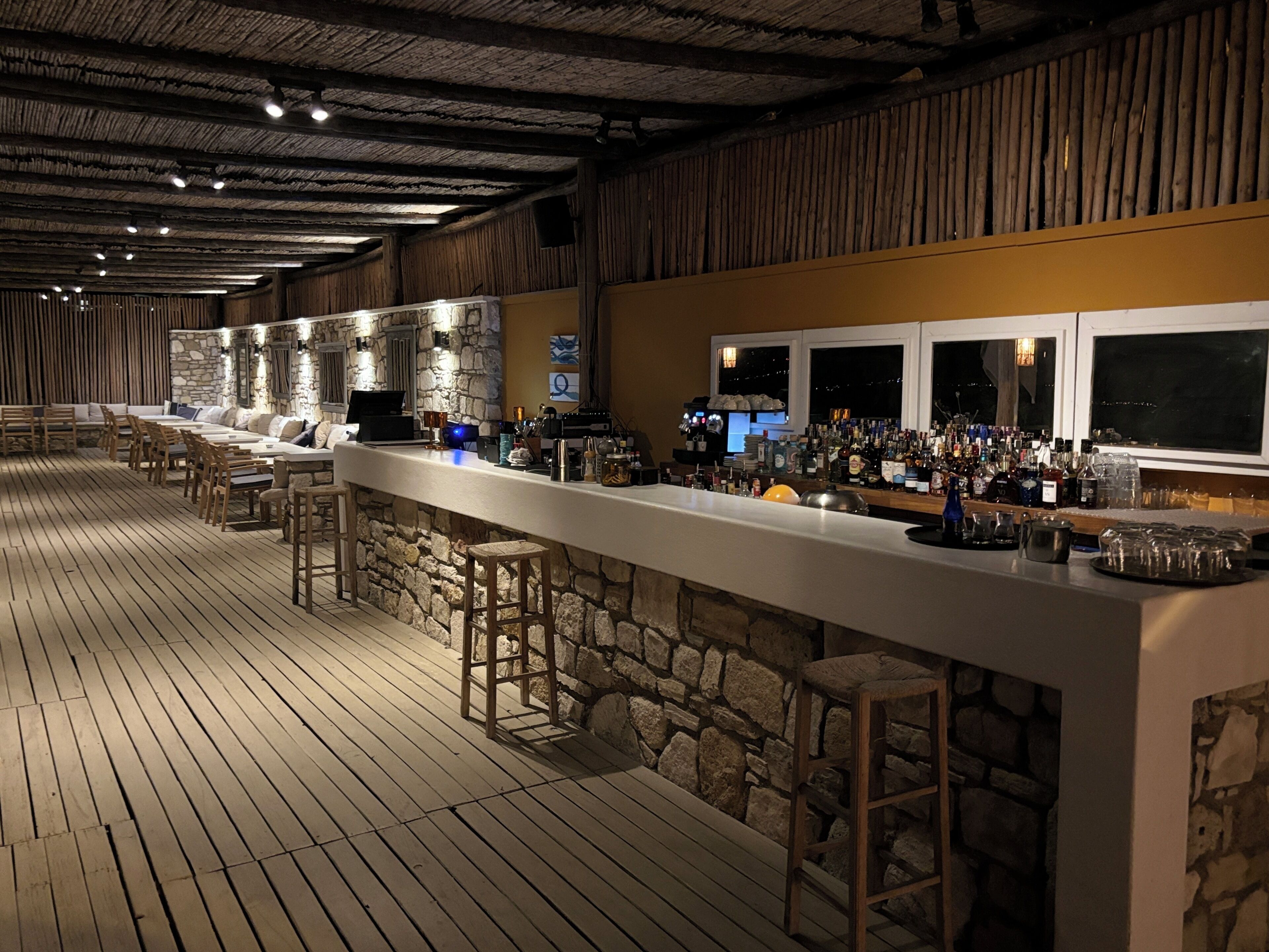 Eine Bar mit einer Steinsäule, Holzboden und Barhocker.