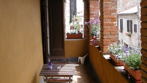 A narrow corridor with a wooden table and benches, brick walls, and potted plants. - B&B Il Glicine Residenza D'Epoca (Torrita di Siena)