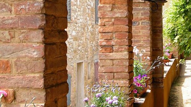 A narrow brick corridor with arches, potted plants, and a stone wall. - B&B Il Glicine Residenza D'Epoca (Torrita di Siena)