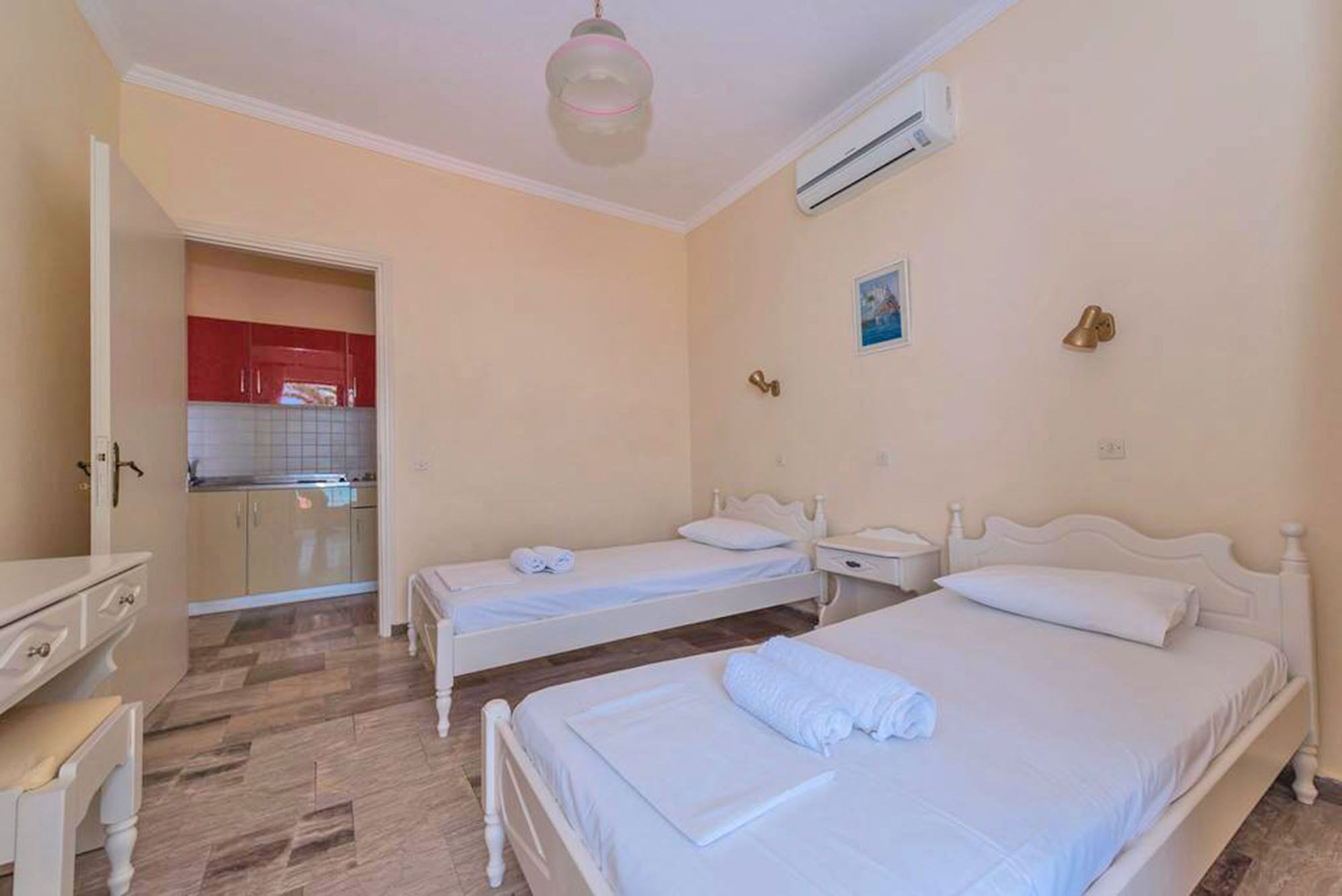 Habitación de hotel con dos camas, kitchenette y ventilador de techo.