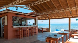 Un bar en bord de mer, avec des meubles en bois et une vue sur l’océan.