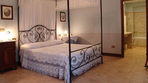 A four-poster canopy bed with a lace bedspread, a wooden nightstand with a lamp, and a framed picture on the wall. - Villa Pardi (Manoppello)