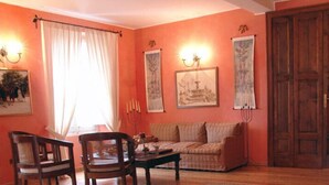 A room with a sofa, chairs, a table, a wooden door, and wall-mounted lights. - Villa Pardi (Manoppello)