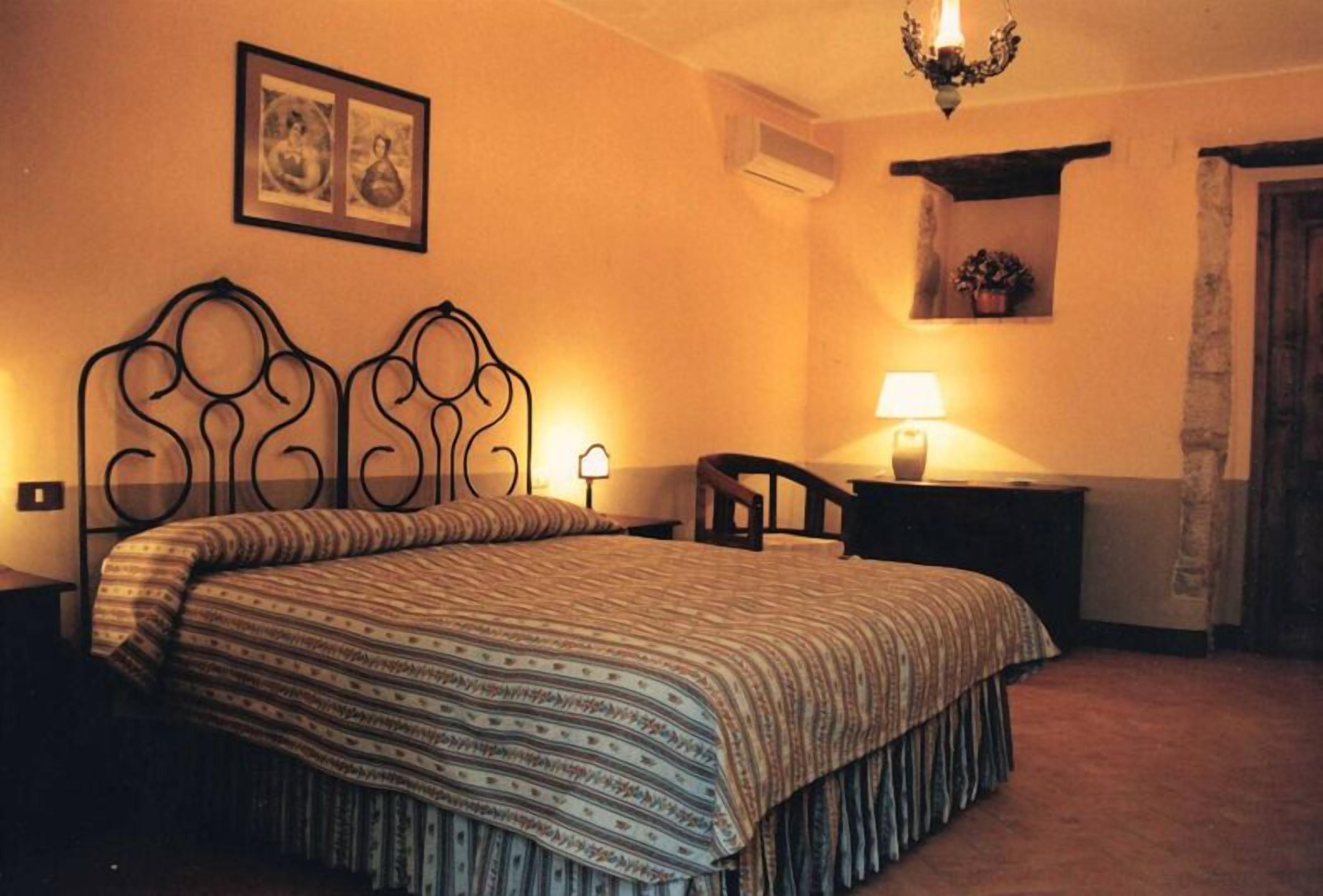 Une chambre à coucher comprenant un lit, une table de chevet, une chaise, une lampe et une étagère fixée au mur, sur laquelle se trouve une plante.