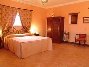 Un dormitorio con una cama, un armario de madera, una silla y una mesita de noche con una lámpara.