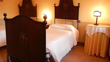 Une chambre d’hôtel avec deux lits, une table ronde avec une lampe et un miroir au mur.
