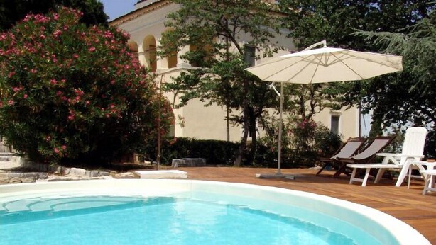A swimming pool with lounge chairs and an umbrella. - Villa Pardi (Manoppello)